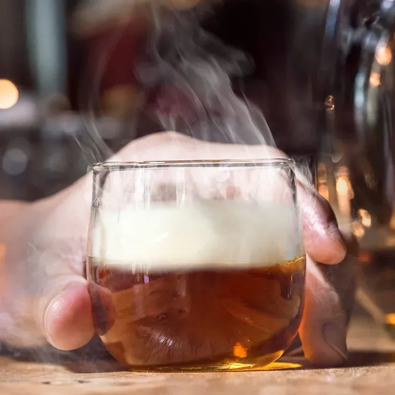 Cocktail Smoker Mixology Bartender Kit in use on a wooden table with smoke and garnishes